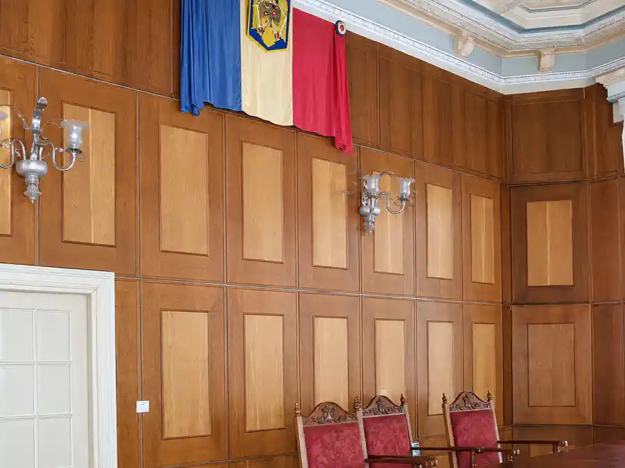 Photographie d’archives de la salle d’audience en service à Casa Băileșteanu, avec drapeau roumain et boiseries murales